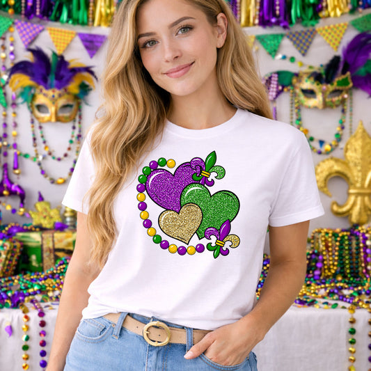 Faux Glitter Mardi Gras Symbols DTF transfer design mockup on a t-shirt featuring MARDI GRAS in faux glitter purple green and gold typography with fleur-de-lis accents