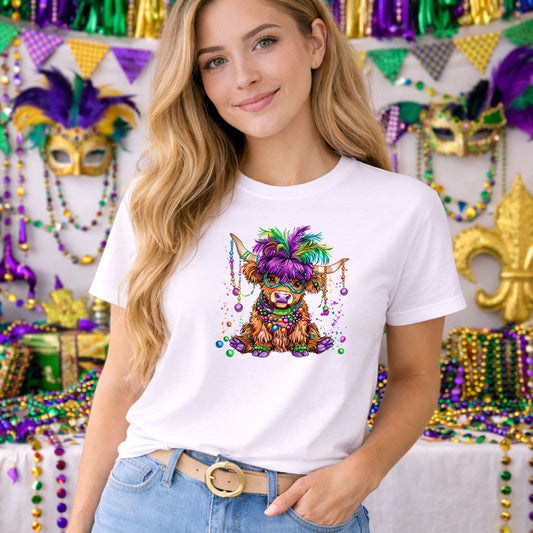 Mardi Gras Highland Cow DTF transfer design mockup on a t-shirt featuring a fluffy highland cow wearing a colorful feathered Mardi Gras mask and bead necklaces