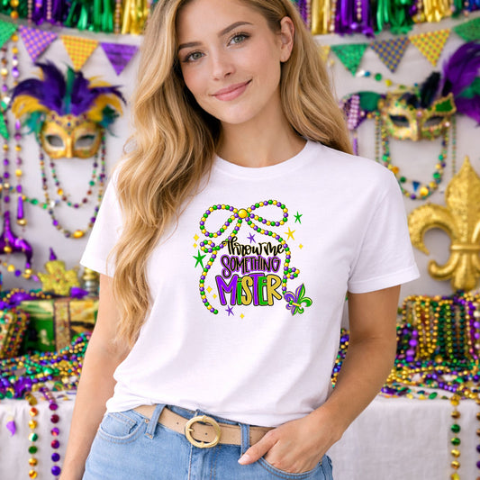 Throw Me Something Mister DTF transfer design mockup on a t-shirt featuring Throw me something MISTER script with Mardi Gras beads and fleur-de-lis accents