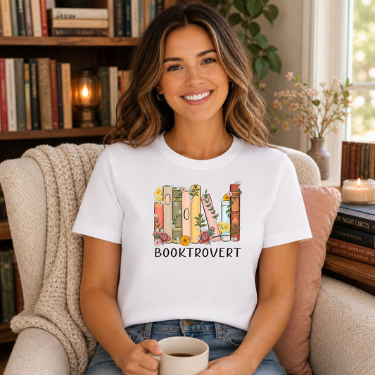 Booktrovert DTF transfer design mockup on a t-shirt featuring a row of standing books with floral accents and bold BOOKTROVERT typography