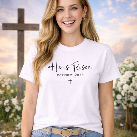 He Is Risen Verse DTF transfer design mockup on a pink t-shirt featuring elegant He is Risen script with Matthew 28:6 and a small cross