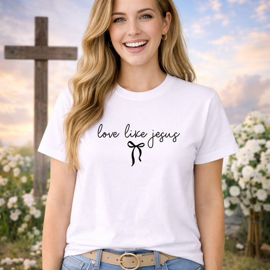 Love Like Jesus Black DTF transfer design mockup on a pink t-shirt featuring delicate love like jesus black script lettering with a small bow