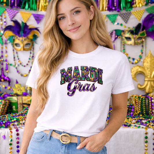 Mardi Gras Rhinestone DTF transfer design mockup on a t-shirt featuring sparkling faux rhinestone MARDI GRAS typography in purple green and gold