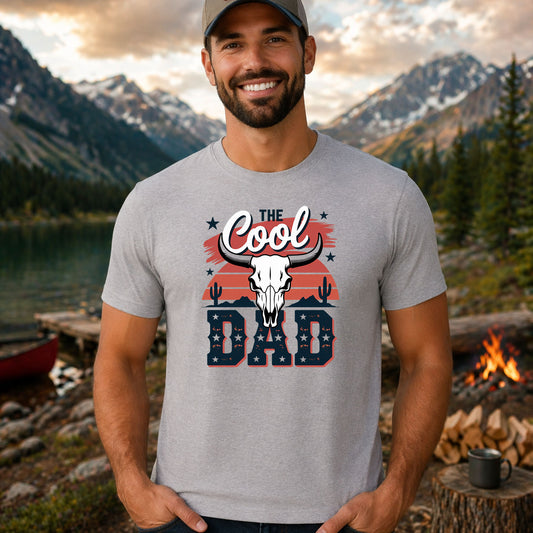 The Cool Dad Western DTF transfer design mockup on a t-shirt featuring a longhorn bull skull against a red sunset with THE COOL DAD typography